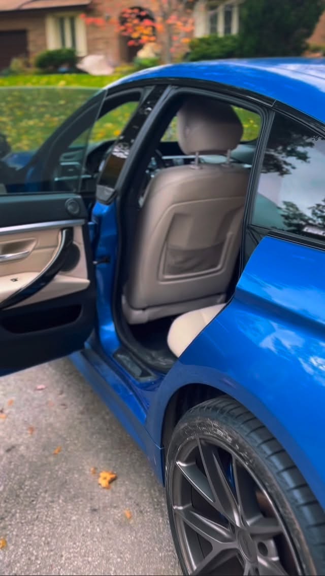 Glossy blue BMW sedan freshly detailed in a residential driveway